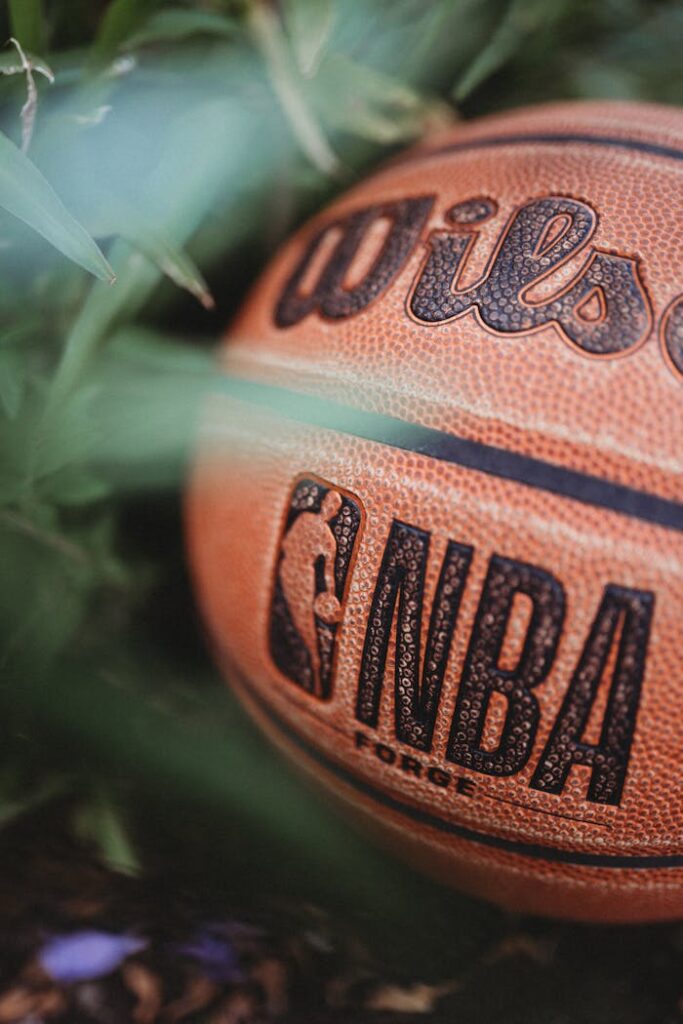 Detailed close-up of a Wilson basketball with NBA logo, surrounded by greenery.